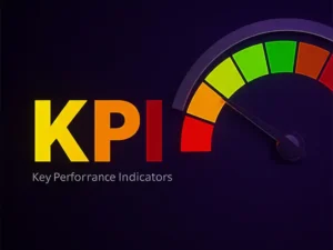 The image features the acronym **KPI**, which stands for **Key Performance Indicators**, written in a bold, modern font. The letters **K**, **P**, and **I** are highlighted in yellow, red, and orange, respectively. To the right of the text, there is a semi-circular gauge or speedometer-like graphic with a needle pointing towards the green section, indicating a positive performance level. The gauge is divided into multiple color-coded segments, ranging from green (good performance) to red (poor performance). The background is dark purple, creating a sleek and professional look.